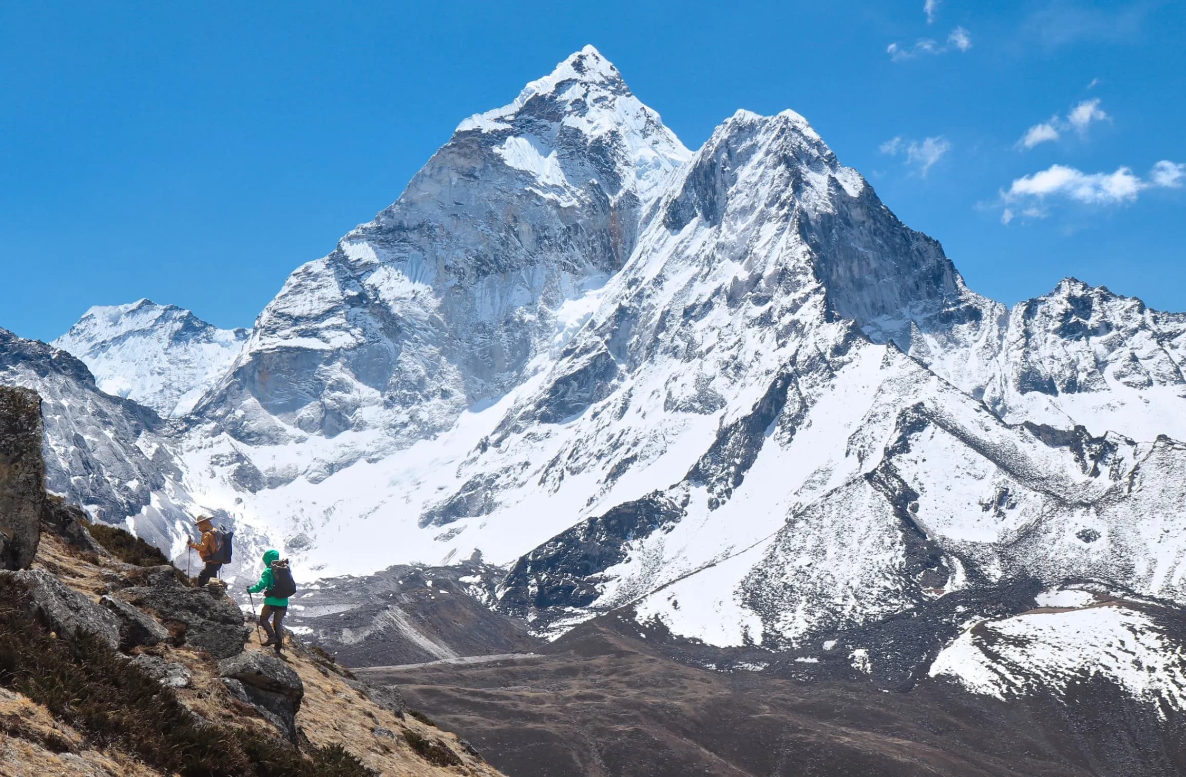 Arka planda karlı Himalaya zirveleri eşliğinde Everest Ana Kampı patikasında yürüyen trekkingciler